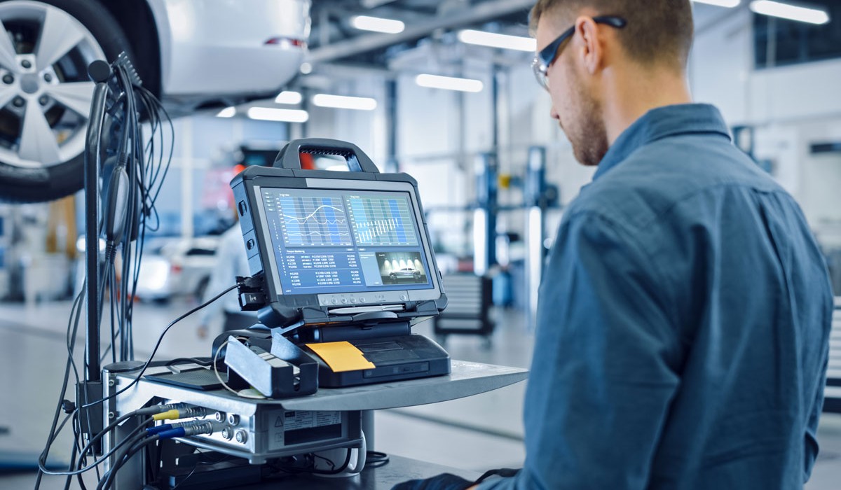 Image of Technician reading data from dealership diagnostic tool connected to rear of vehicle. 